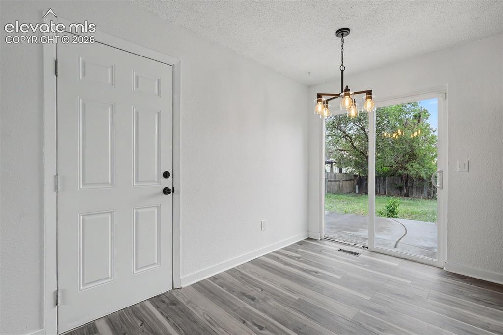 Image 21 of 43: Bright interior featuring wood-finish flooring, a contemporary chandelier, 