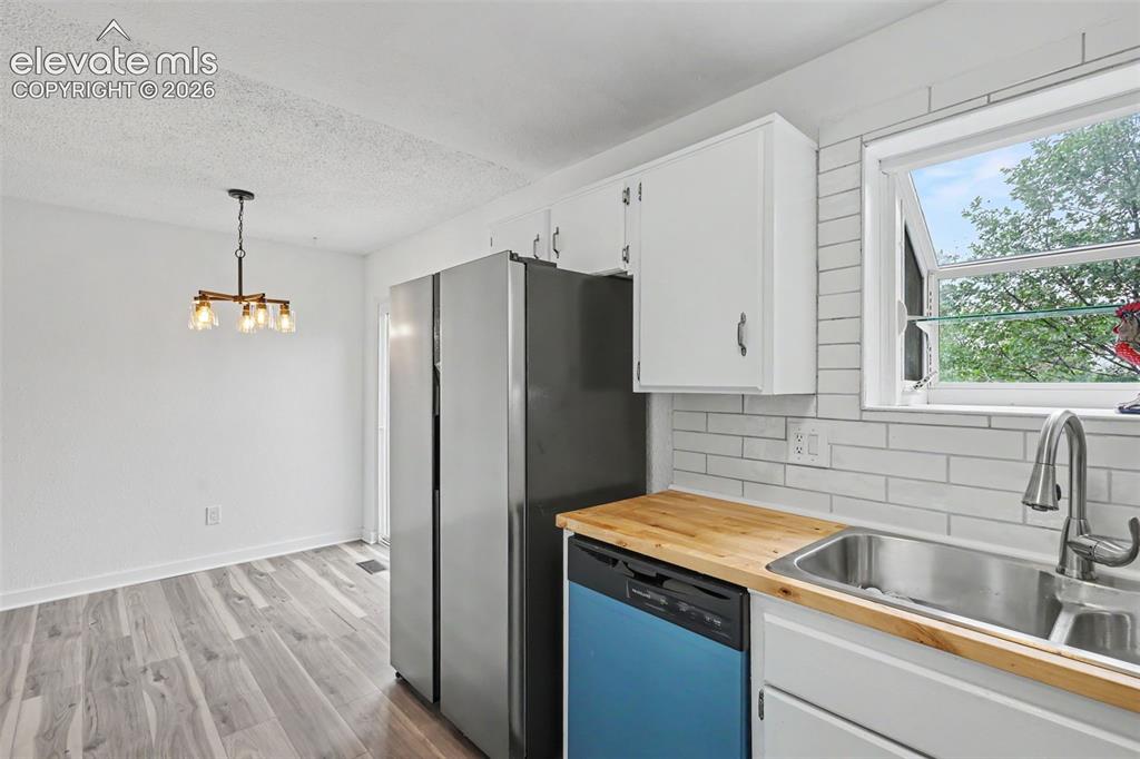 Image 23 of 43: Modern kitchen featuring wood-finish countertops, subway tile backsplash, s