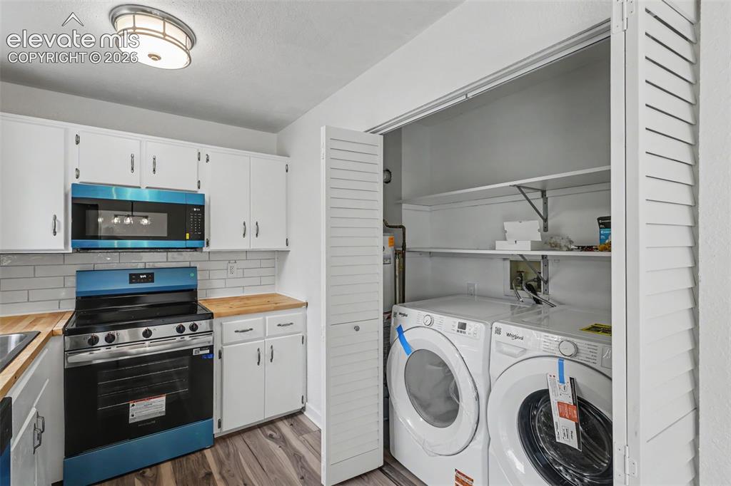 Image 26 of 43: Modern kitchen appliances with white cabinetry, wood-finish countertops, an