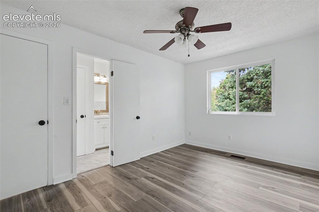 Image 29 of 43: Room featuring wood-finish flooring, white walls, and a ceiling fan