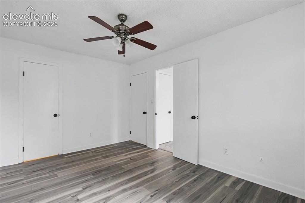 Image 30 of 43: Room featuring wood-finish flooring, white walls, and a ceiling fan with li