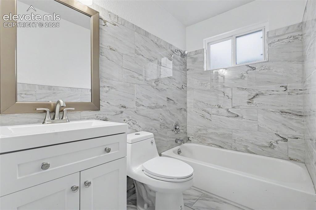Image 31 of 43: Bathroom featuring a white vanity with integrated sink, brushed nickel fauc