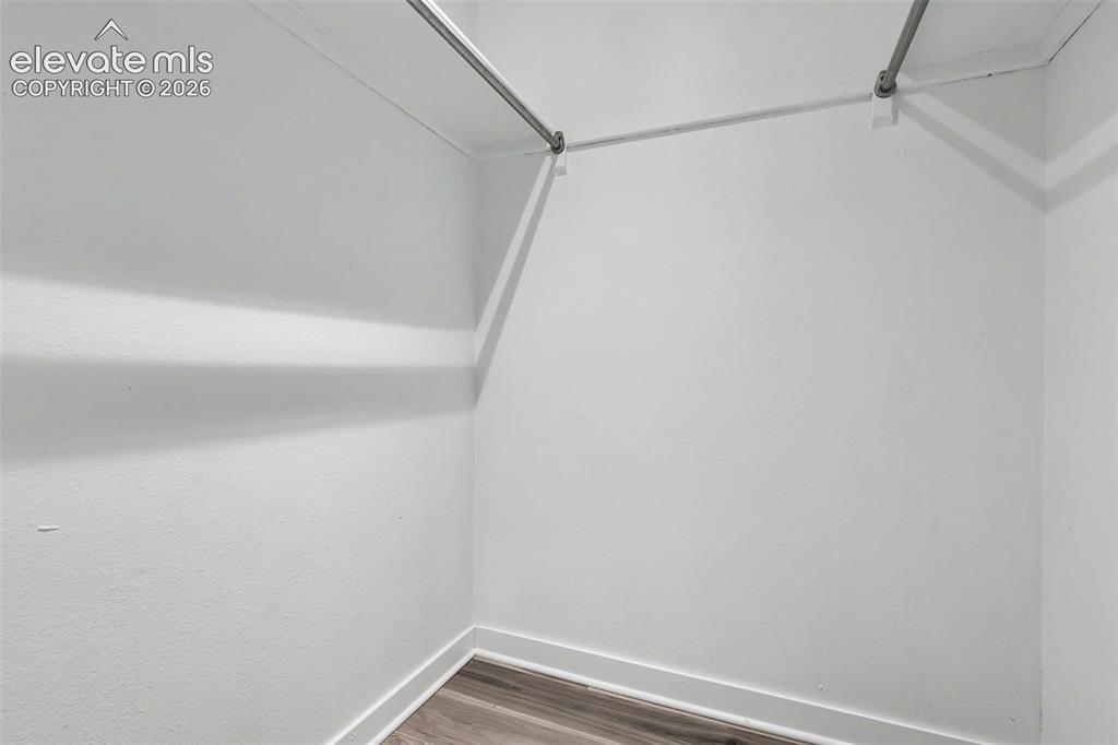 Image 39 of 43: Walk-in closet featuring white painted walls, wood-finish flooring, and two