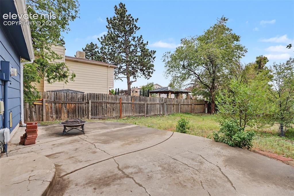 Image 40 of 43: Expansive concrete patio area with a wooden privacy fence