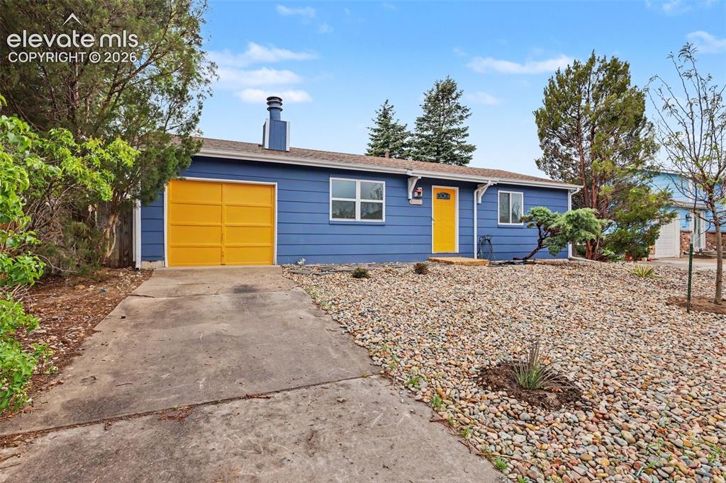 Image 9 of 43: Single-story residence featuring blue siding with a contrasting yellow gara