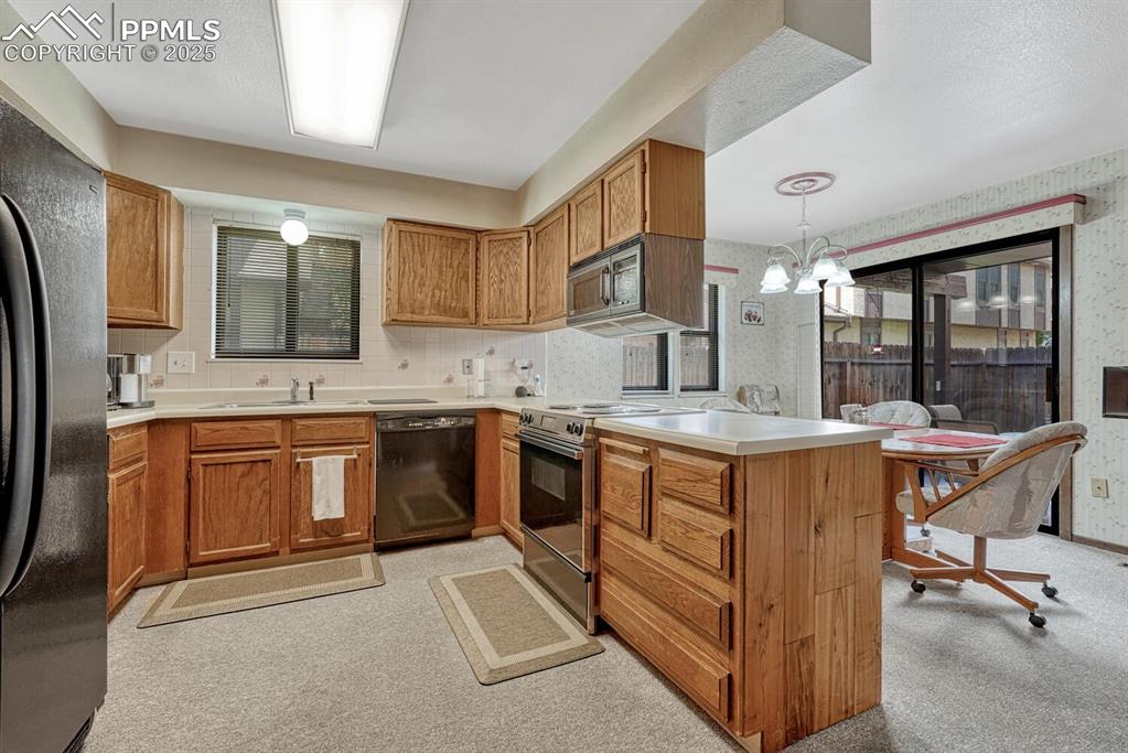 Image 10 of 32: Dining area featuring wallpapered walls, light colored carpet, and a chande
