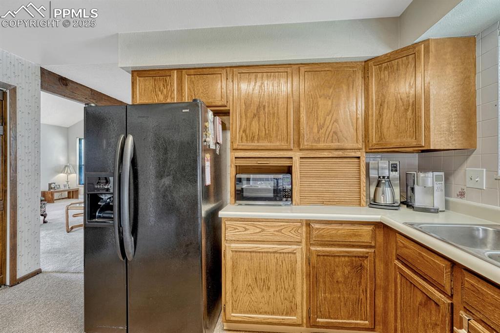 Image 13 of 46: Kitchen featuring black appliances, light colored carpet, light countertops
