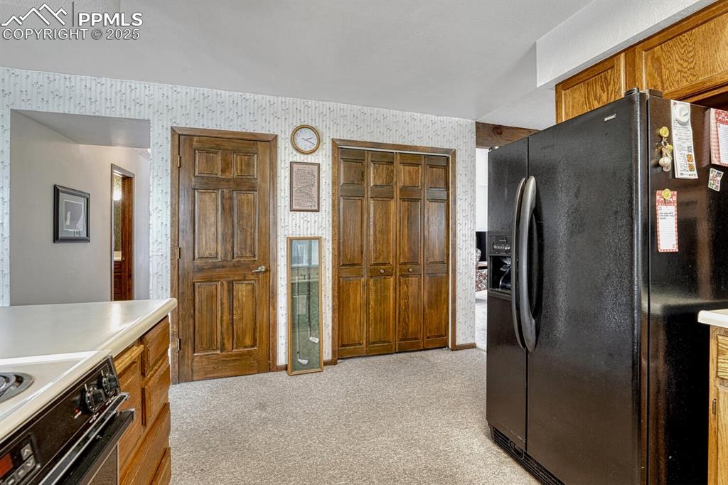 Image 14 of 46: Kitchen featuring black refrigerator with ice dispenser, light colored carp