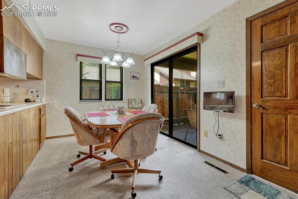 Image 16 of 46: Dining area with light carpet, a chandelier, and wallpapered walls
