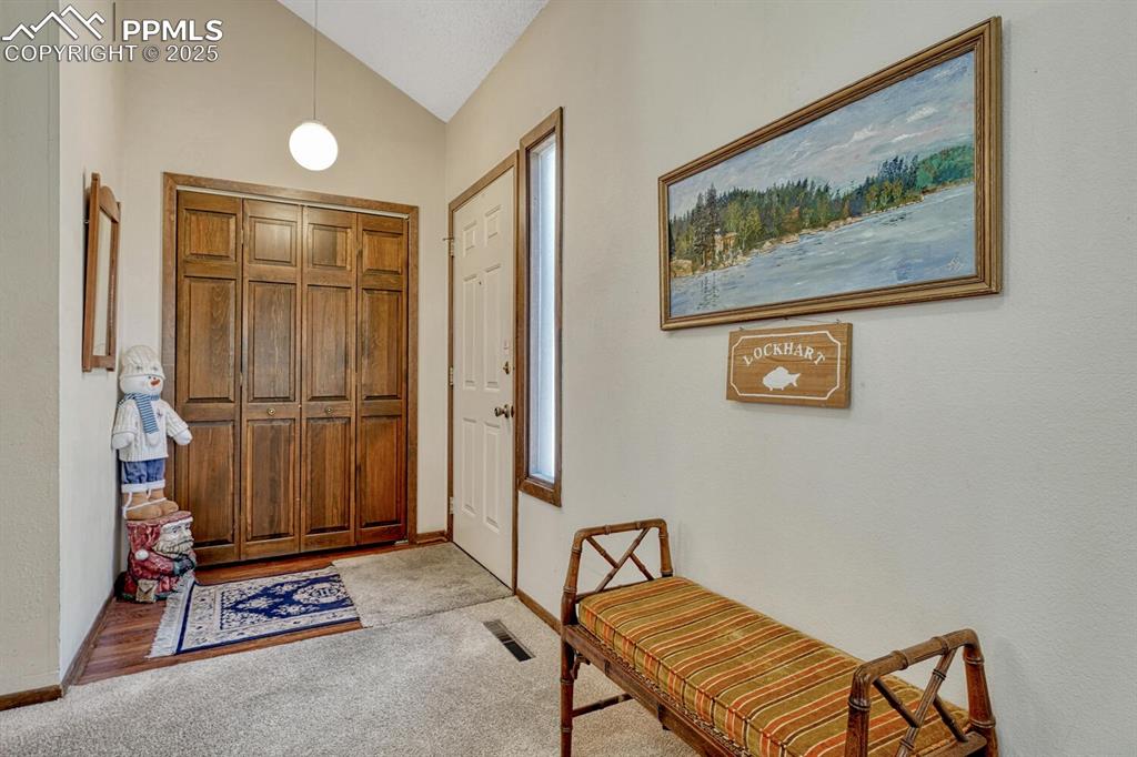 Image 2 of 32: Entryway featuring lofted ceiling and light carpet