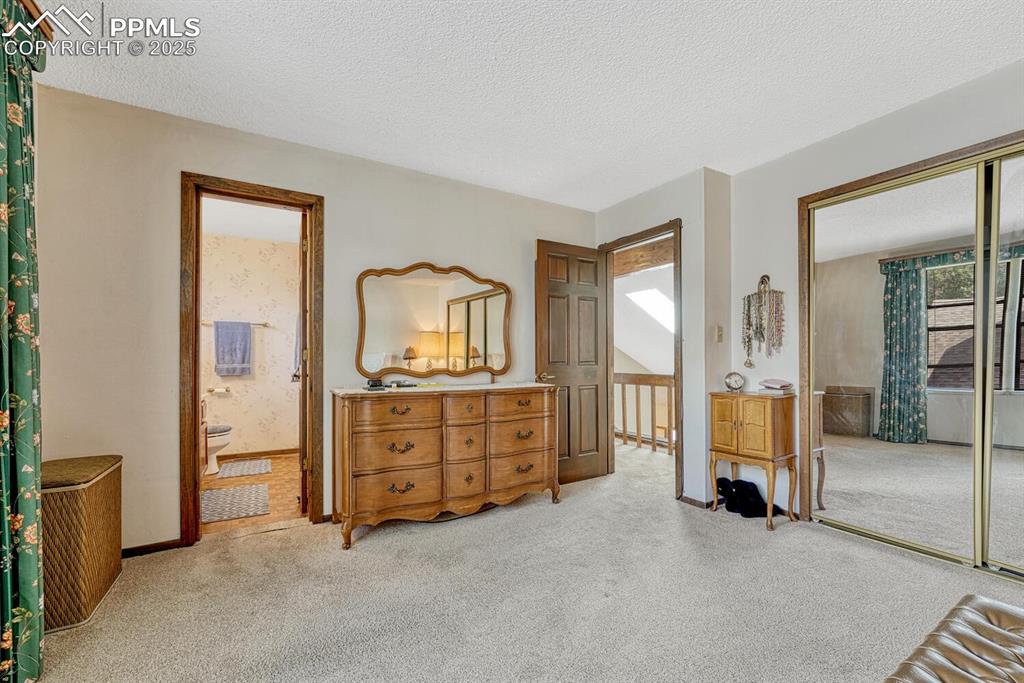 Image 25 of 46: Bedroom featuring a textured ceiling, light colored carpet, and a closet