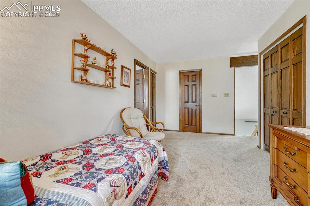 Image 29 of 46: Carpeted bedroom with a textured ceiling and baseboards