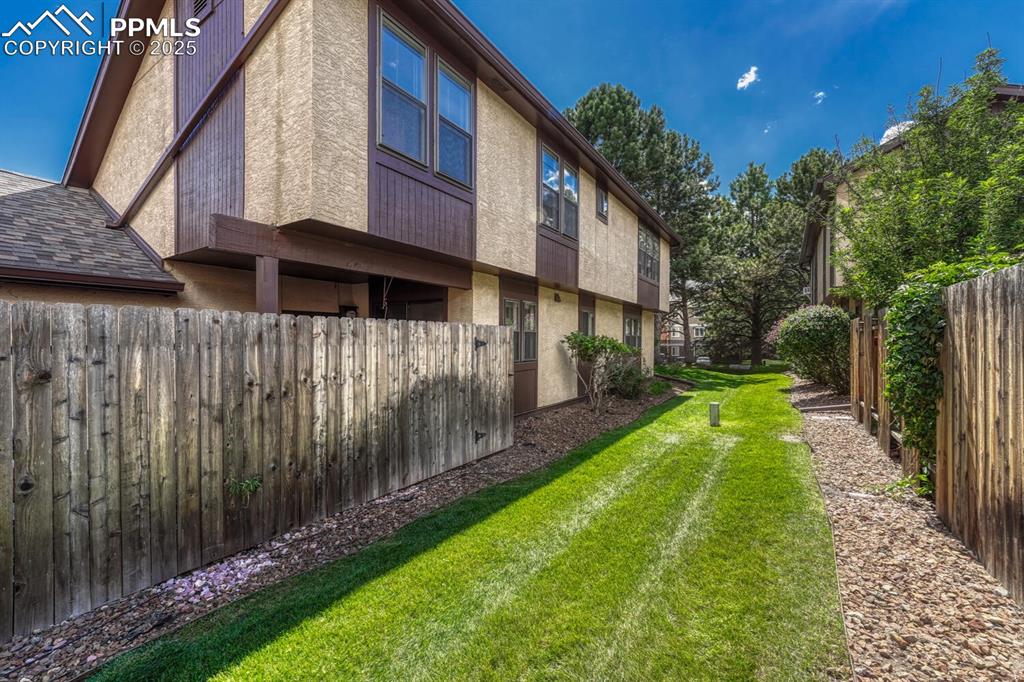 Image 40 of 46: View of side of property with stucco siding and a fenced backyard