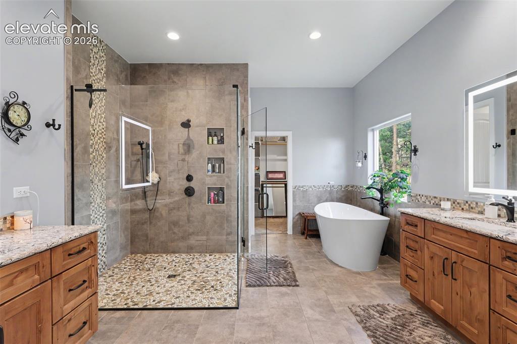 Image 28 of 48: Spacious bathroom featuring a frameless glass shower with pebble flooring a