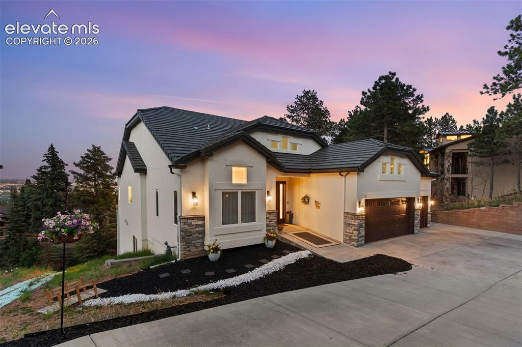 Image 4 of 48: Contemporary stucco exterior with dark tile roofing and stone accents