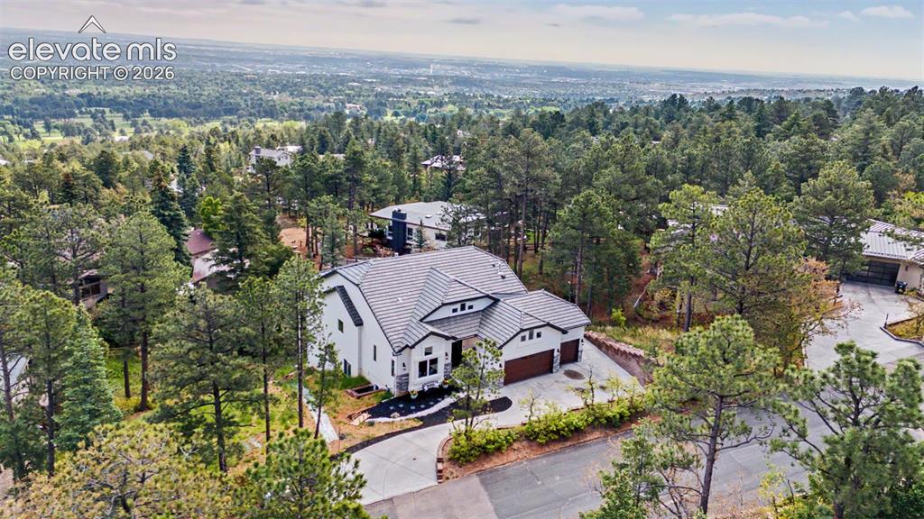 Image 6 of 48: Contemporary residence surrounded by mature pine trees, featuring a white e