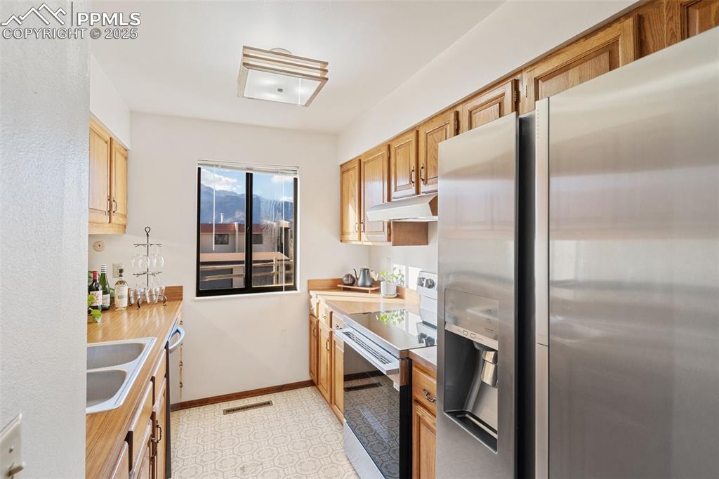 Image 14 of 28: The galley kitchen offers a new refrigerator, stove and vent hood.