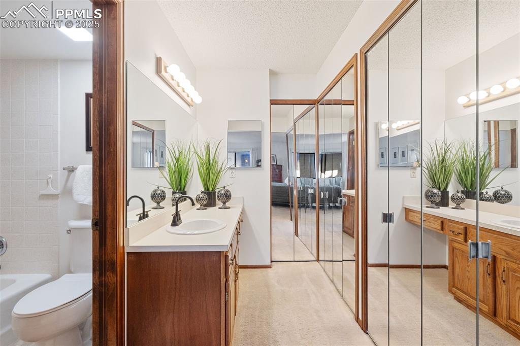 Image 23 of 28: The primary bath includes this mirrored dressing area with a wall of closet