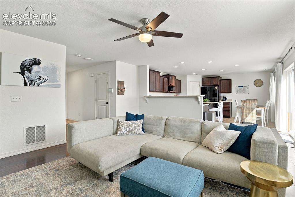 Image 11 of 48: Open-concept living area featuring a ceiling fan with integrated lighting,