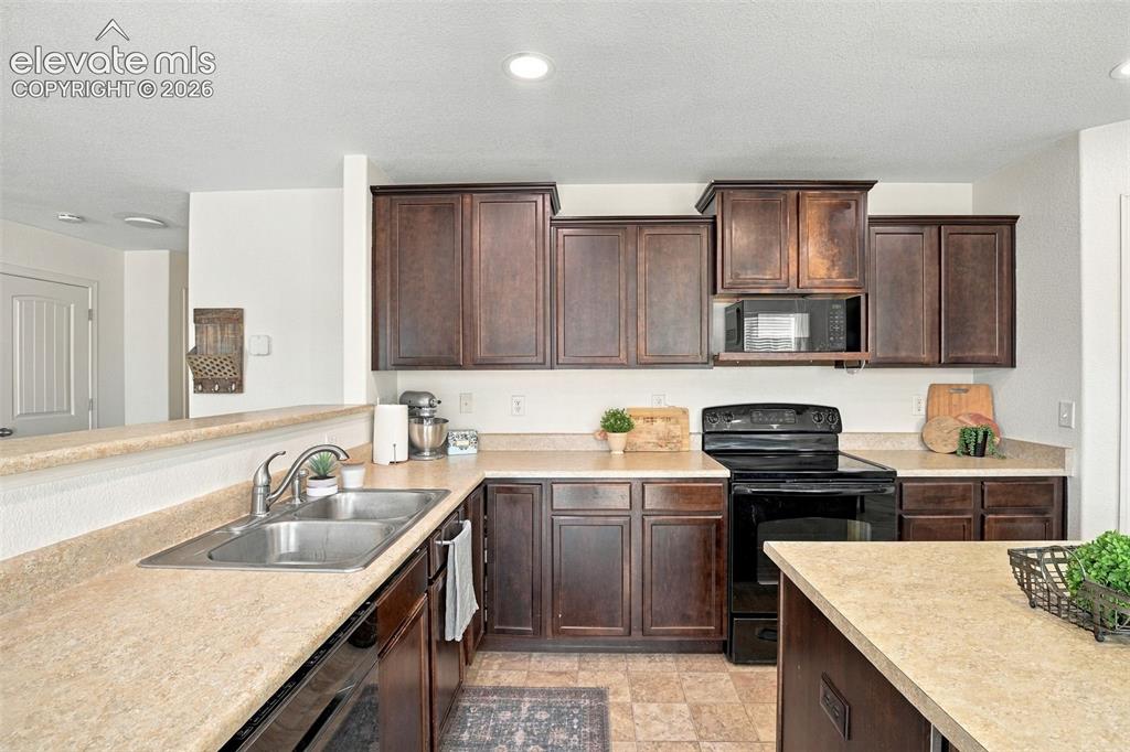 Image 14 of 48: U-shaped kitchen featuring wood-finish cabinetry, a double basin sink, and