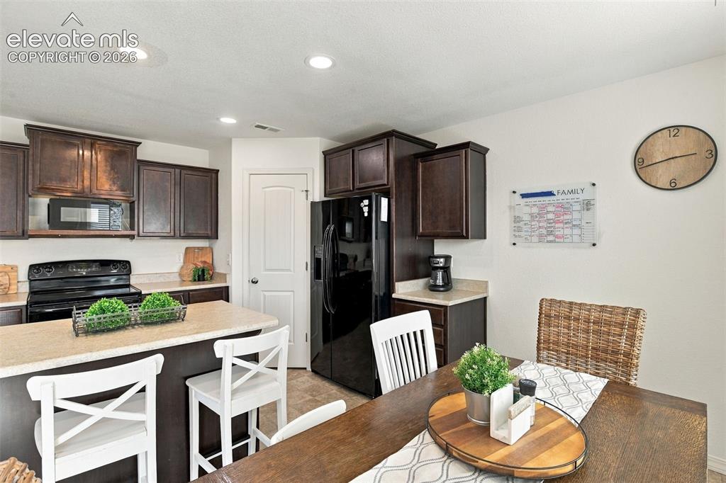 Image 21 of 48: Kitchen featuring dark wood-finish cabinetry, black appliances, light-toned