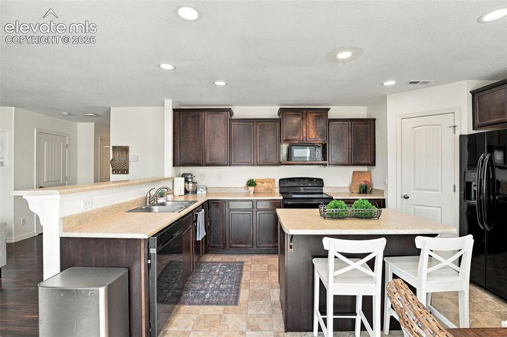 Image 22 of 48: Kitchen featuring dark wood-finish cabinetry, light-toned countertops, and 