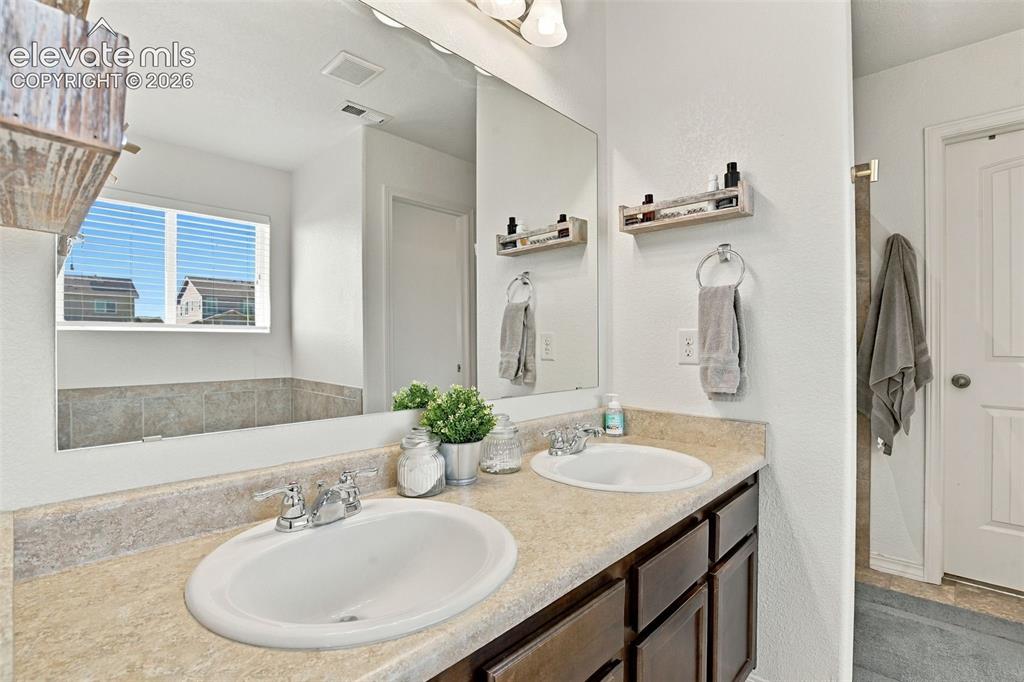 Image 28 of 48: Dual vanity with integrated sinks, framed mirror, and built-in cabinetry