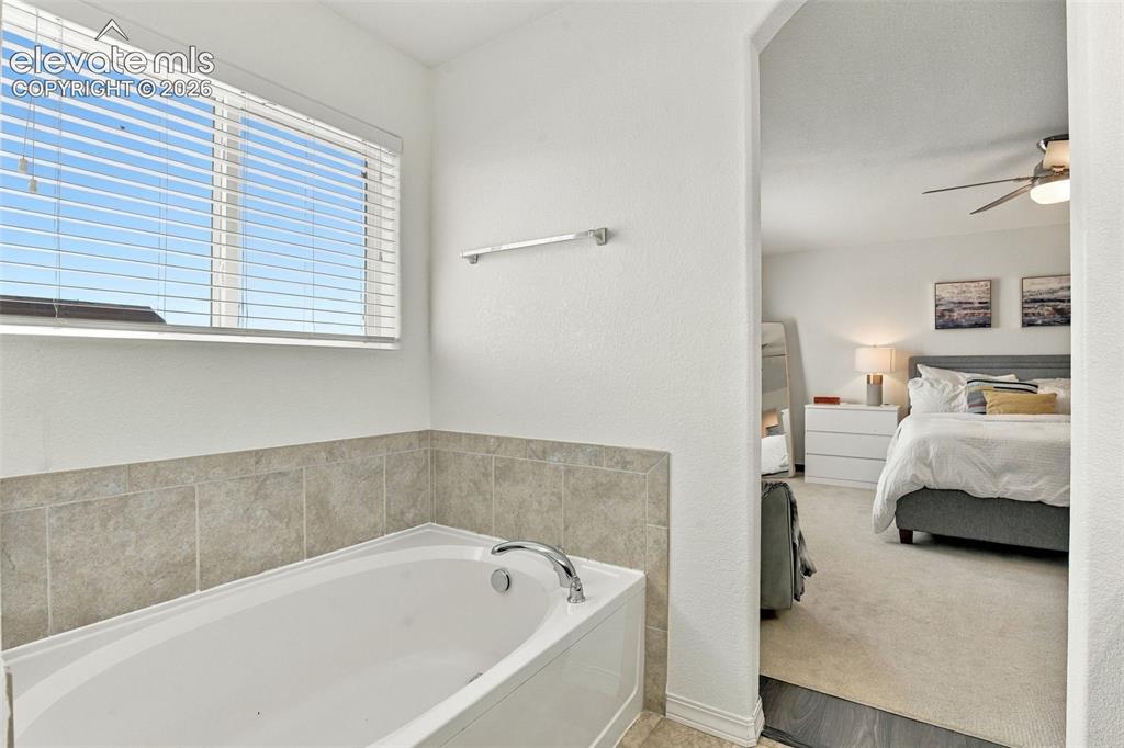 Image 30 of 48: Built-in soaking tub with tile surround, window with horizontal blinds, and