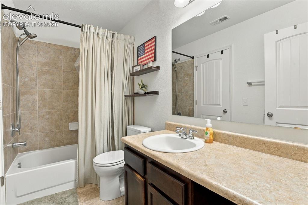 Image 33 of 48: Vanity with an integrated sink, a large mirror, and a bathtub with tiled wa