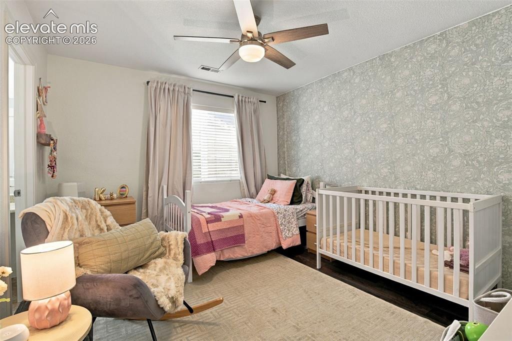 Image 34 of 48: Patterned accent wall, window with blinds, ceiling fan with integrated ligh