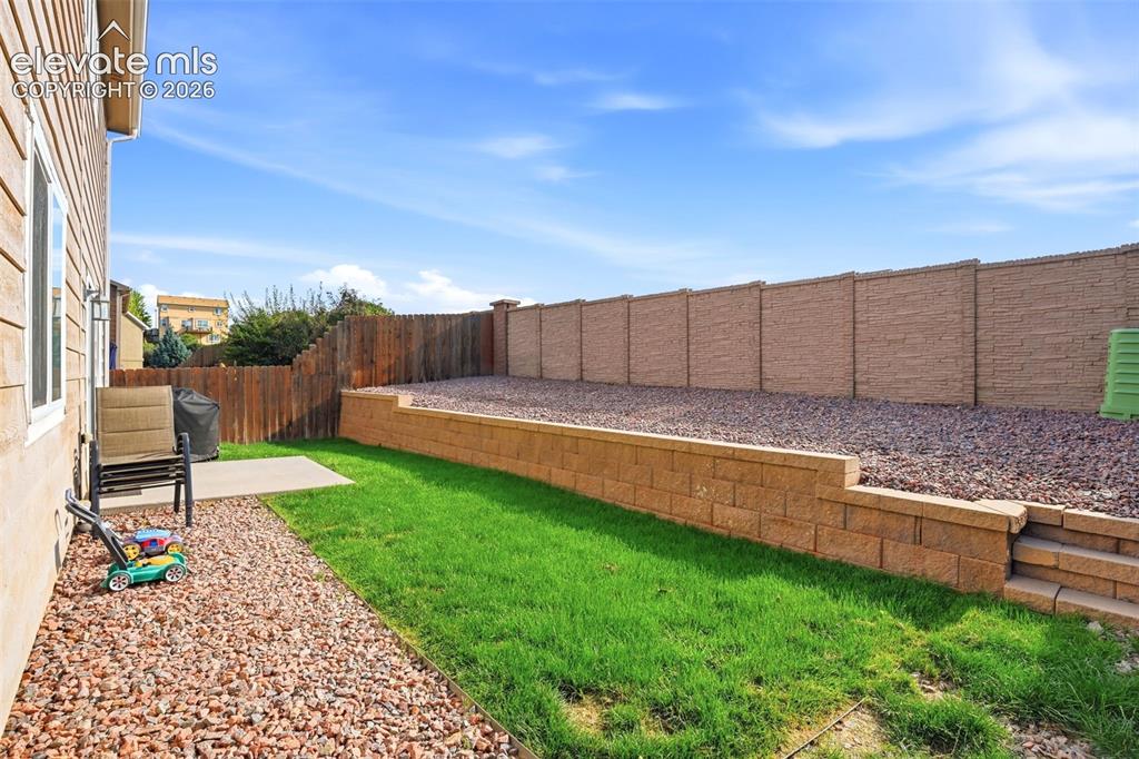 Image 39 of 48: Private backyard featuring a concrete patio, retaining wall with integrated