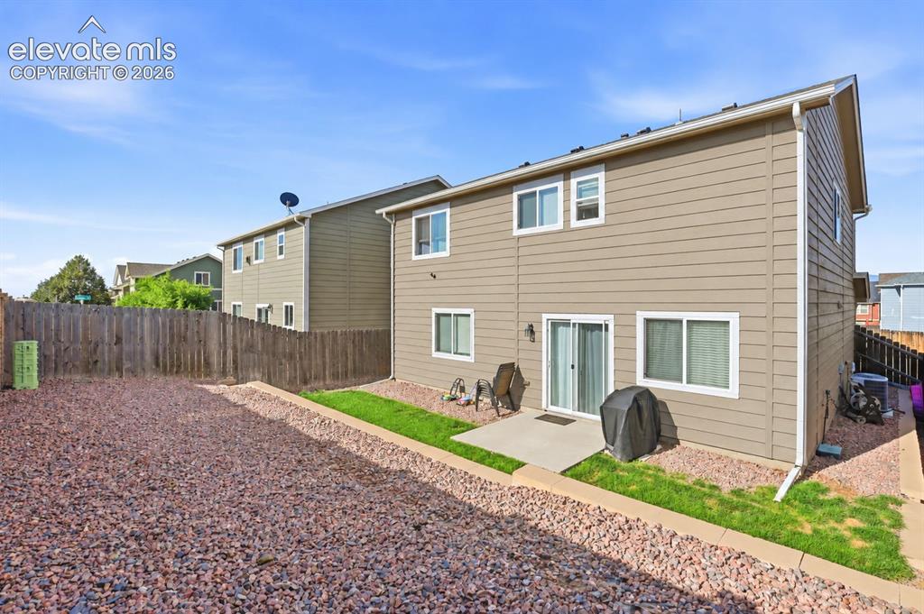 Image 41 of 48: Rear exterior featuring a sliding glass door, an outdoor patio, and a fence
