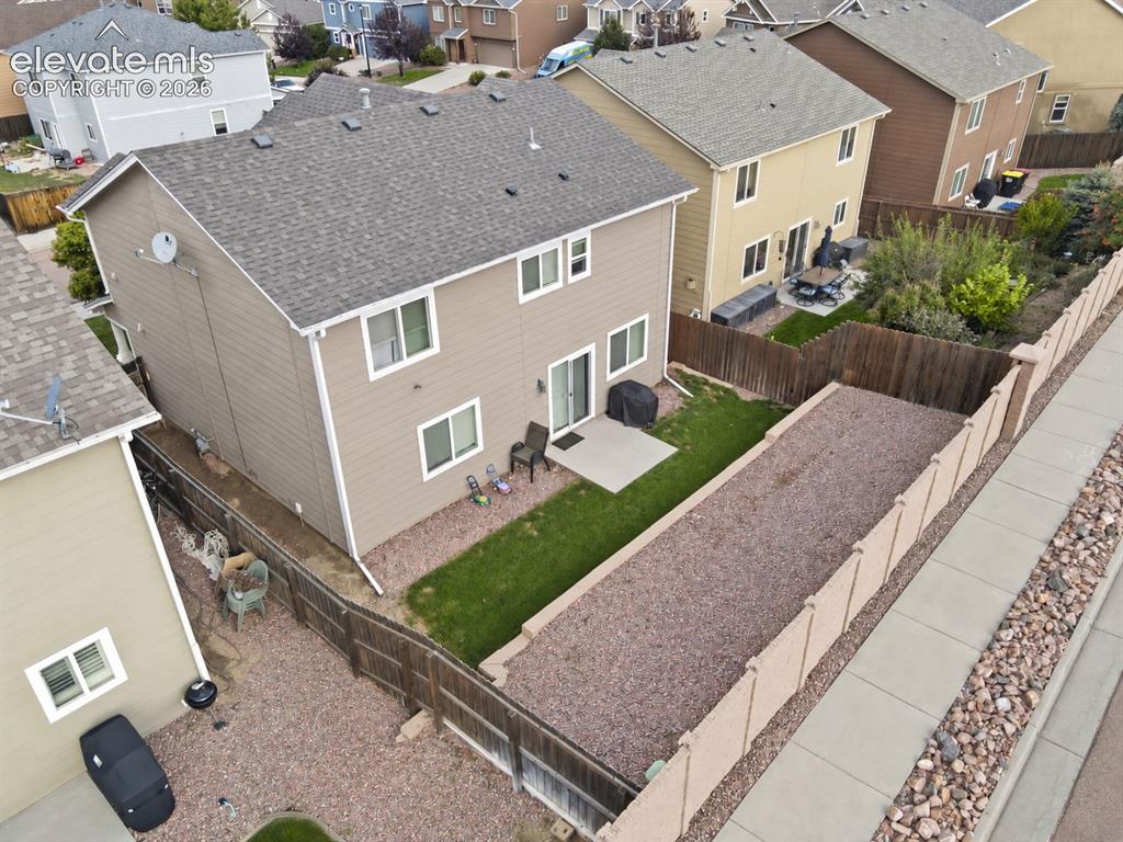 Image 43 of 48: Two-story property with a gravel roof, tan siding, and a concrete patio