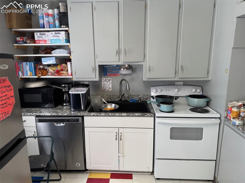 Image 7 of 33: Kitchen featuring white range with electric stovetop, black microwave, a si