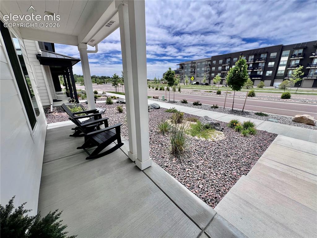 Image 2 of 20: Covered concrete front porch with white siding and columns