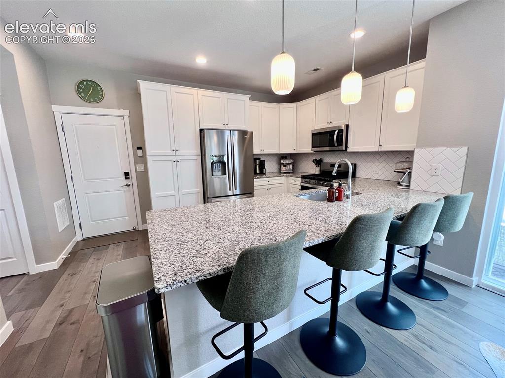 Image 6 of 20: Kitchen featuring a large central island with a light-toned, speckled count