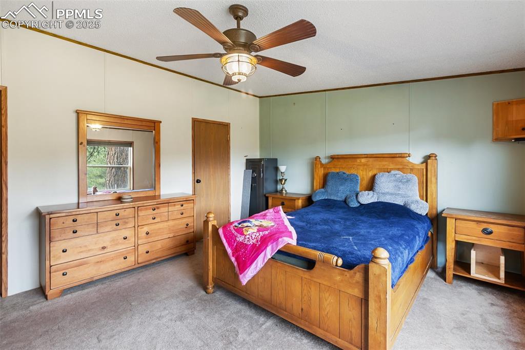 Image 23 of 37: Bedroom featuring crown molding, light carpet, ceiling fan, and a textured 
