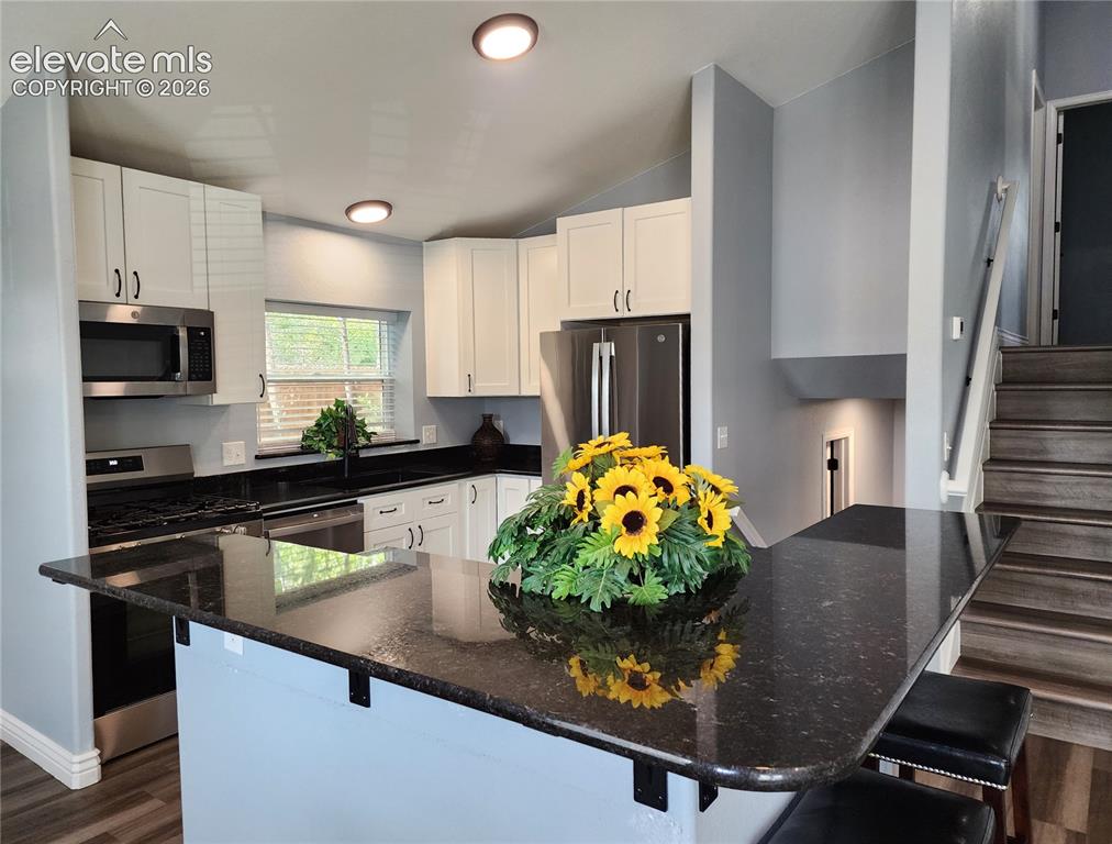 Image 6 of 49: Gourmet kitchen featuring elegant dark granite countertops and ample cabine