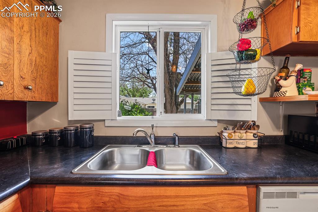 Image 12 of 27: Views of the backyard from standing at the stainless steel double sink.