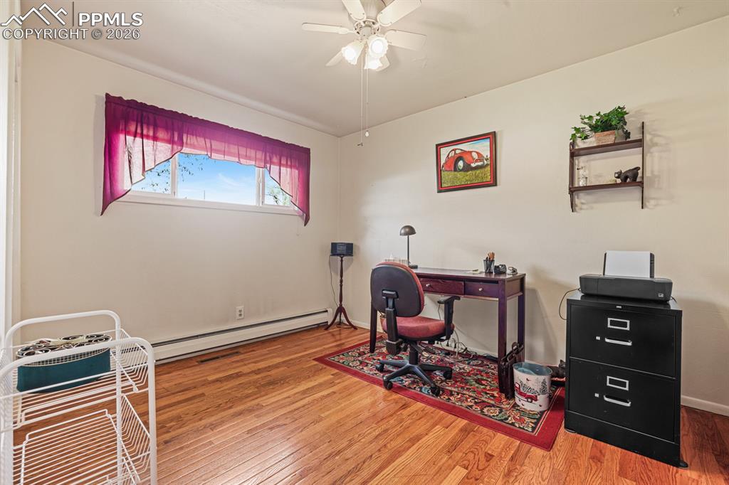 Image 19 of 27: Bedroom #2 (currently an office) has a lighted ceiling fan and hardwood flo