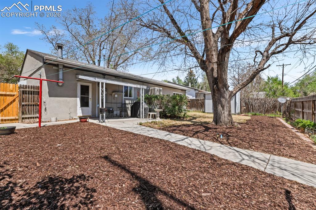 Image 21 of 27: Fenced xeriscaped backyard with auto sprinklers, mature trees and shrubs, a