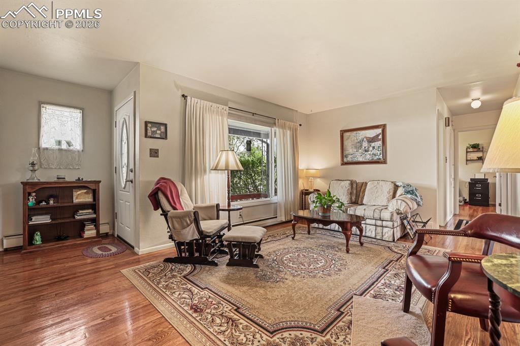 Image 4 of 27: The front door leads into a bright, spacious Living Room with hardwood floo