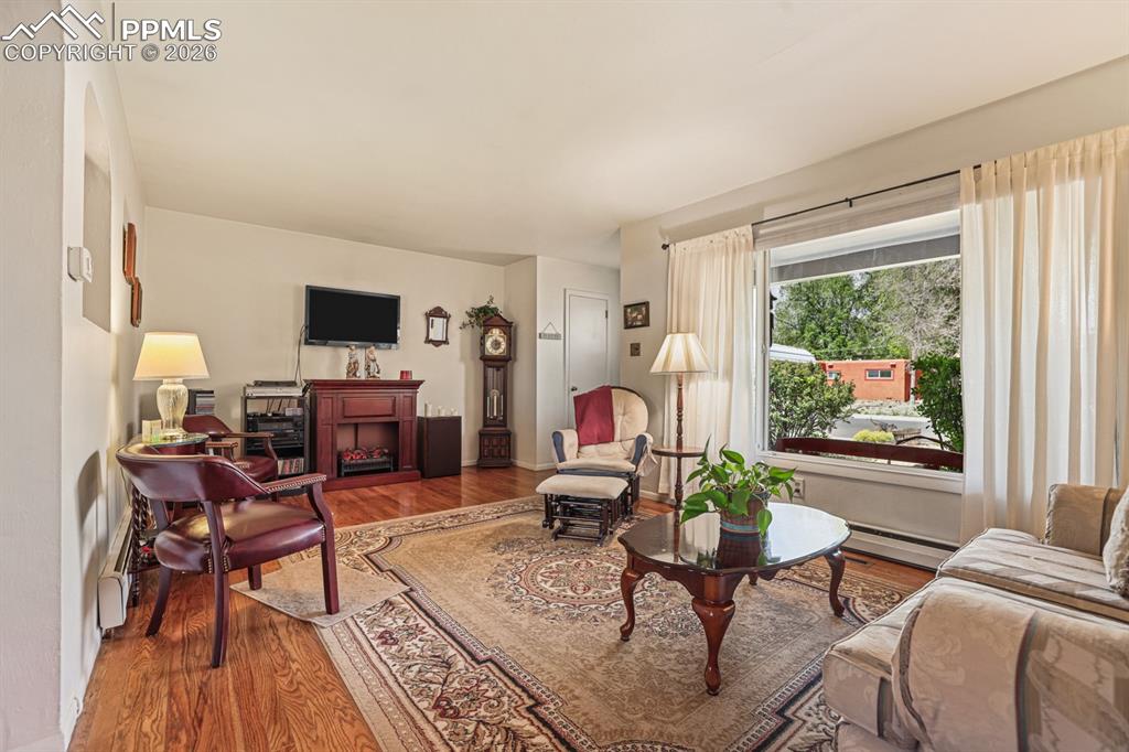Image 6 of 27: The Living Room boasts gleaming hardwood floors and a large window with fro