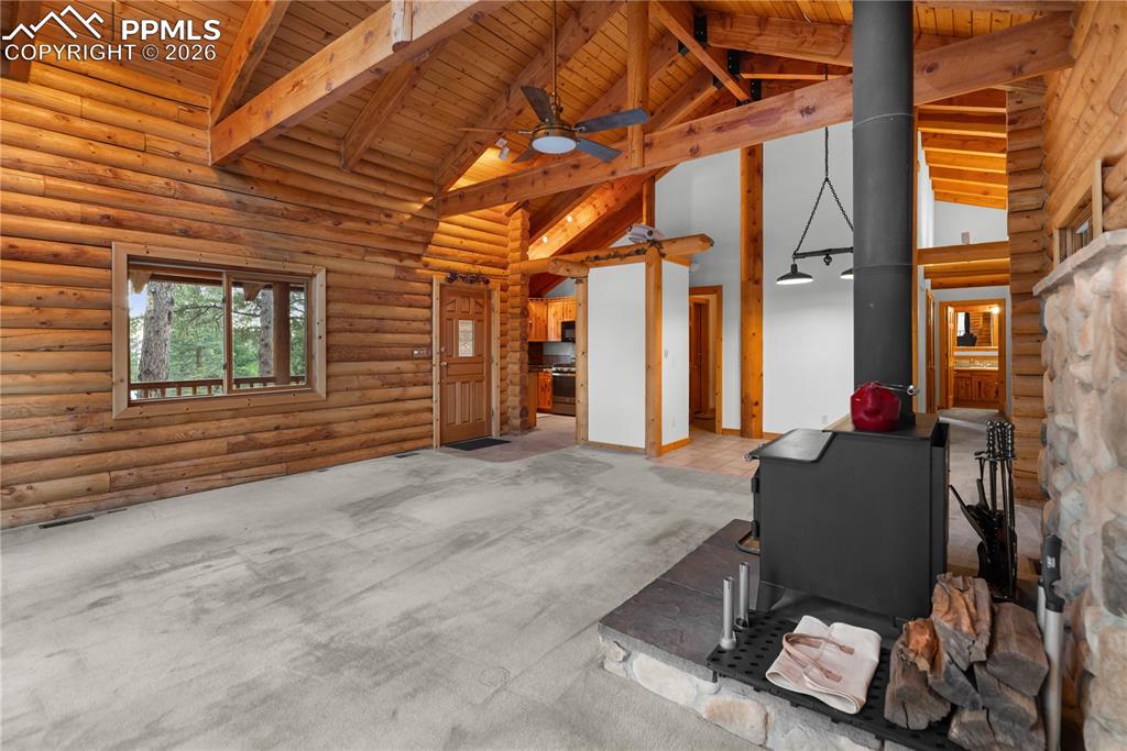 Image 14 of 45: Living room with a wood stove, high vaulted ceiling, ceiling fan, a wooden