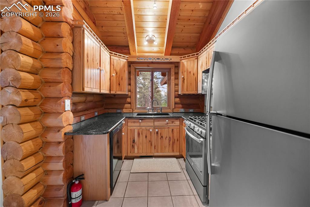 Image 17 of 45: Kitchen featuring stainless steel appliances, wood ceiling, log walls, ligh