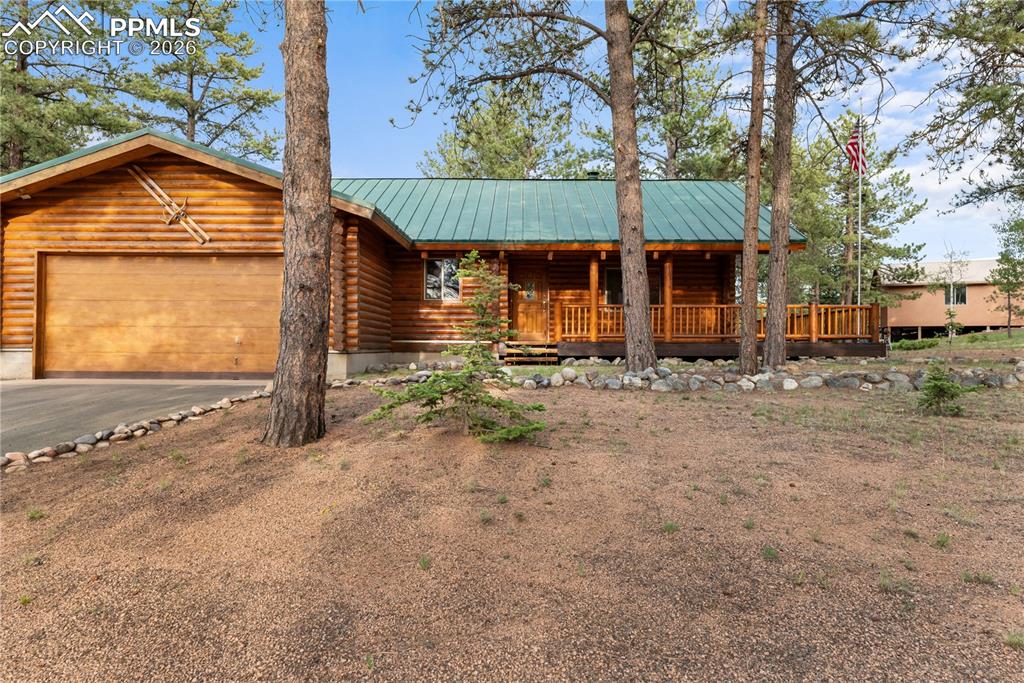 Image 2 of 45: Log cabin featuring covered porch, log siding, asphalt driveway, an attache