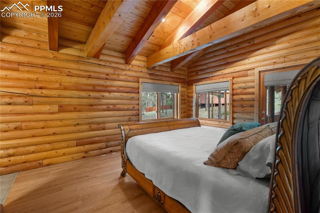 Image 20 of 45: Bedroom with wood finished floors, wood ceiling, and log walls