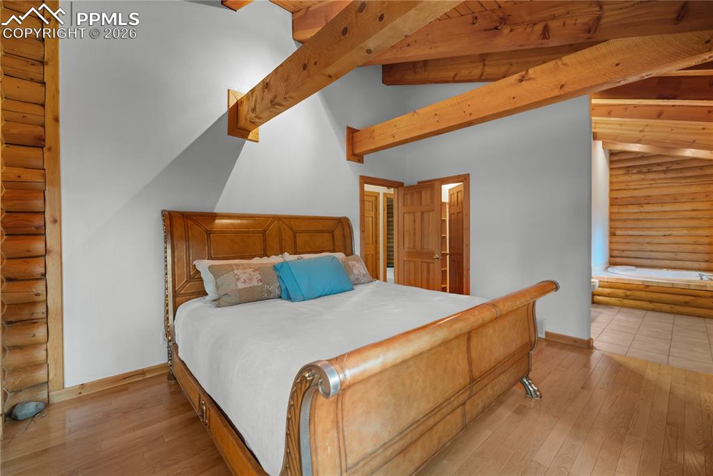 Image 21 of 45: Bedroom with rustic walls and hardwood / wood-style flooring