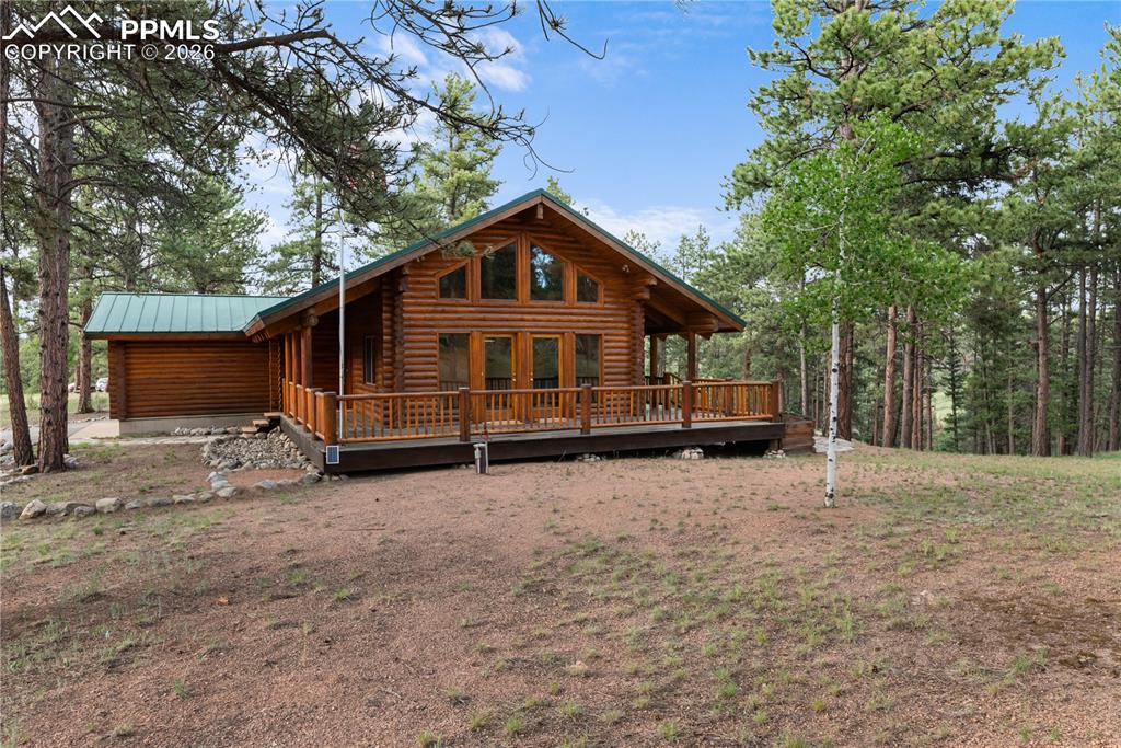 Image 3 of 45: View of front of property featuring log exterior, a wooden deck, and a meta
