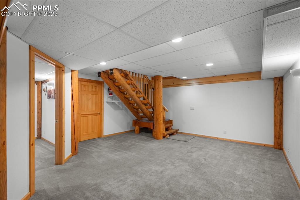 Image 30 of 45: Finished basement with carpet, stairs, recessed lighting, and a paneled cei